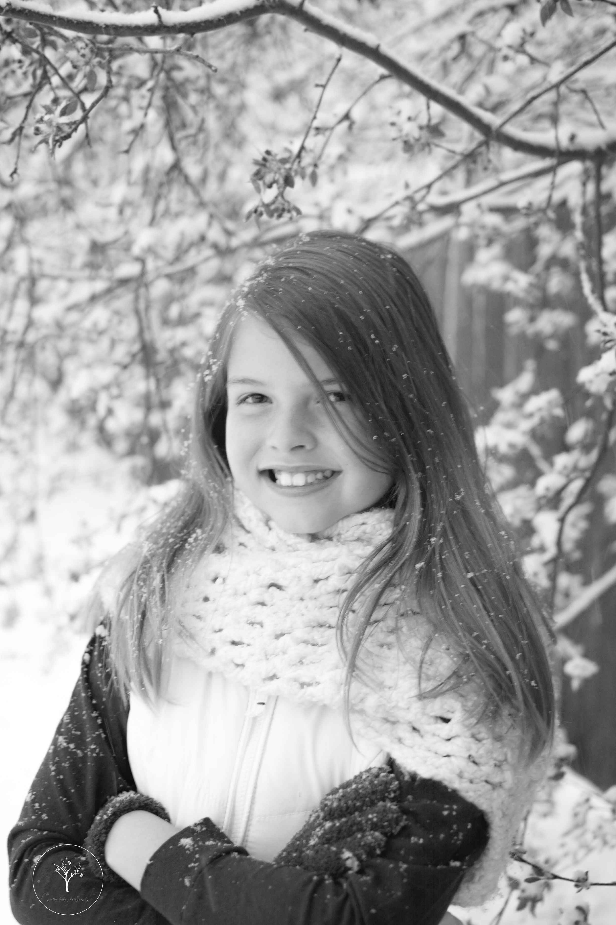 Black and white winter portrait amidst snow-covered tree branches.