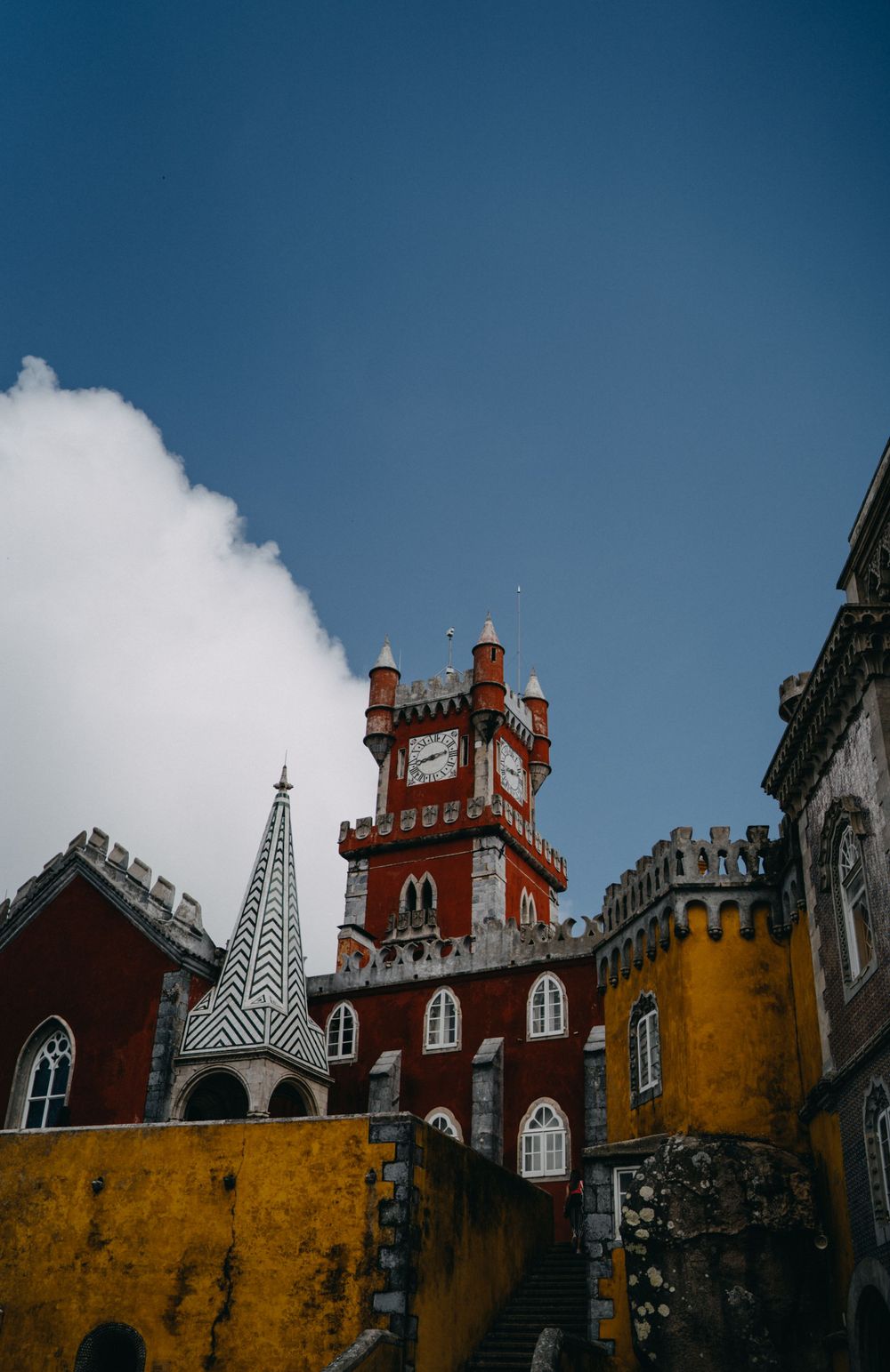 Pena Palace's colorful towers and Gothic architecture against bright blue sky in Sintra.