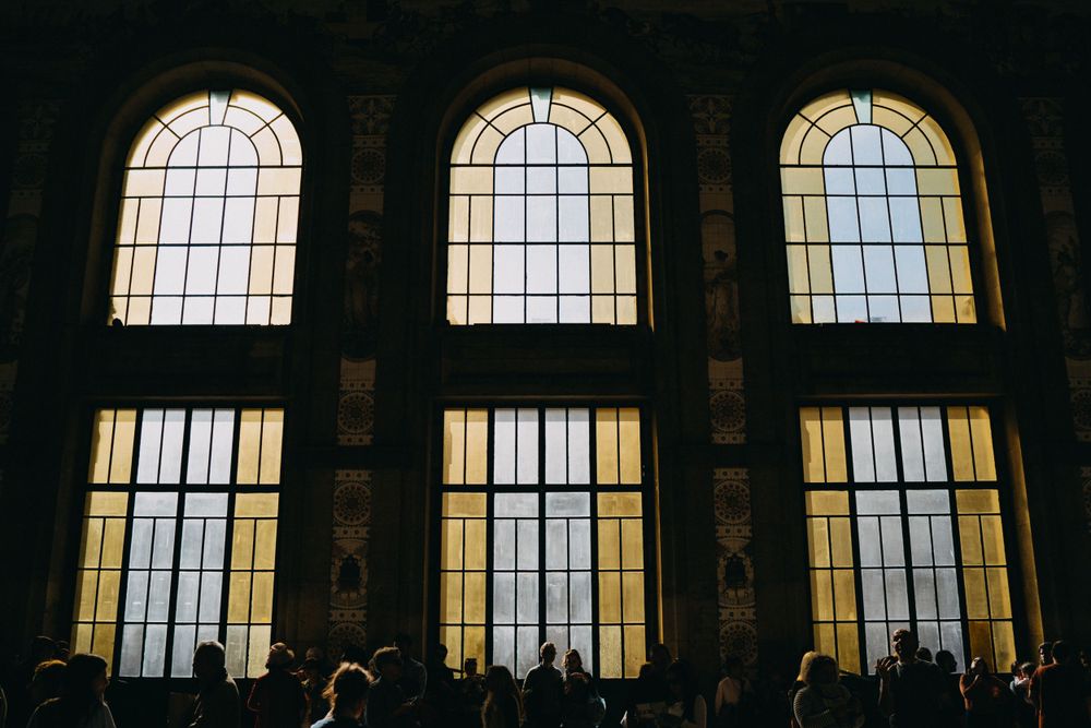 Row of tall arched windows silhouetted against warm interior lighting.
