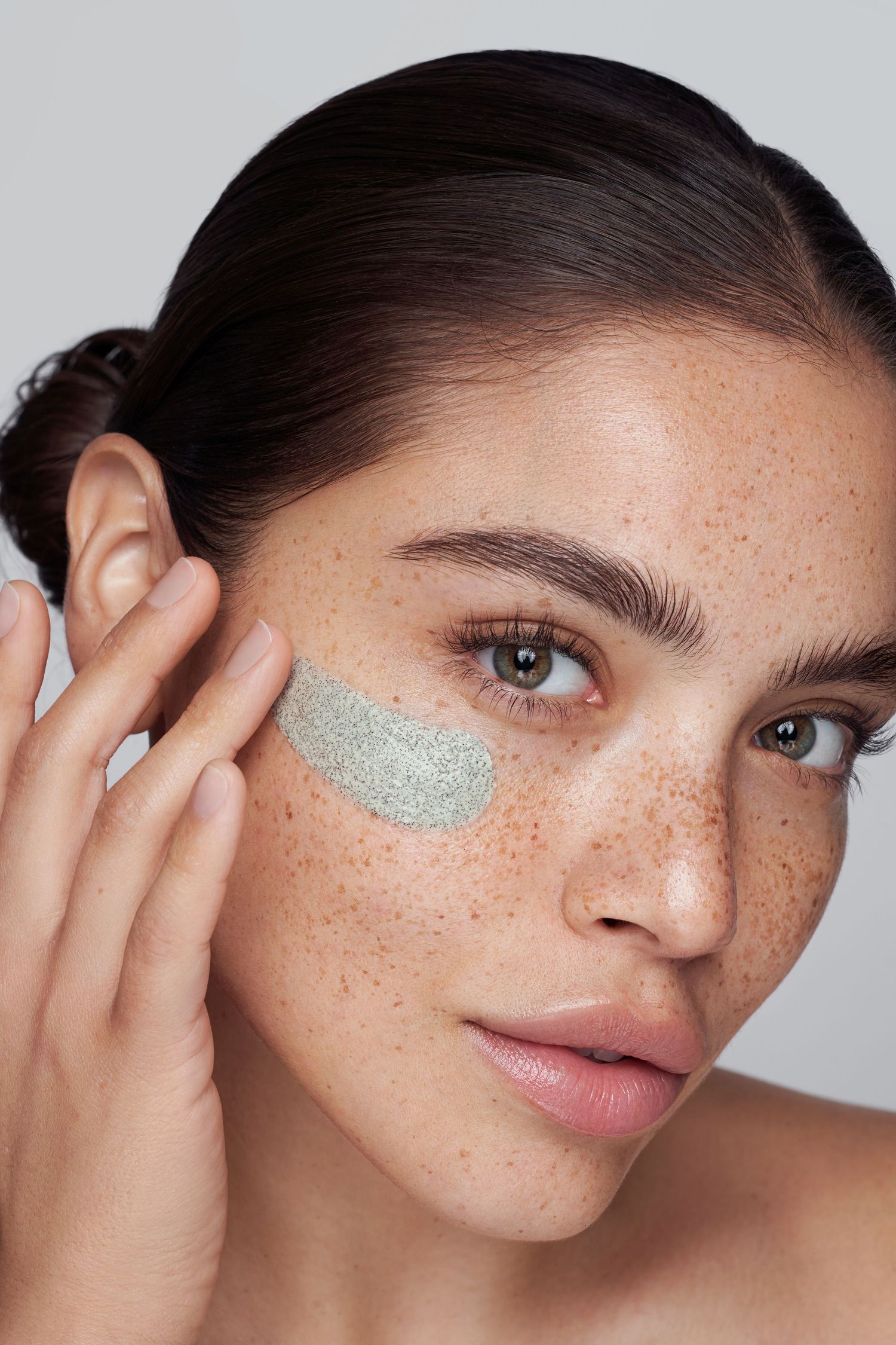 Skincare beauty shot with silver glitter patch and natural freckles on bare skin.