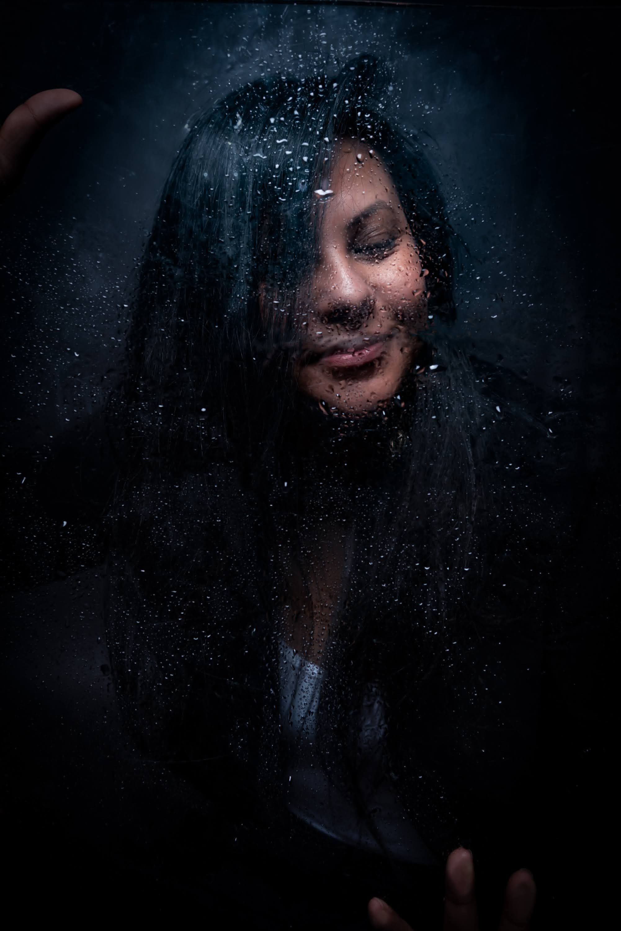 Femme derrière une vitre de pluie