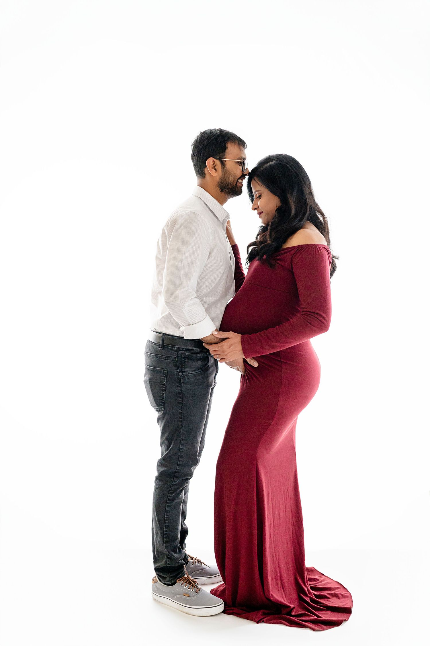 Couple sharing intimate moment during maternity photoshoot in studio.