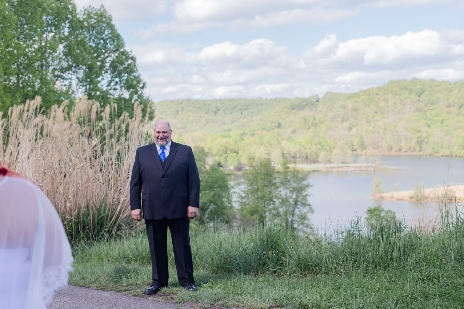 Wedding ceremony setup overlooking a serene lake surrounded by hills and trees.