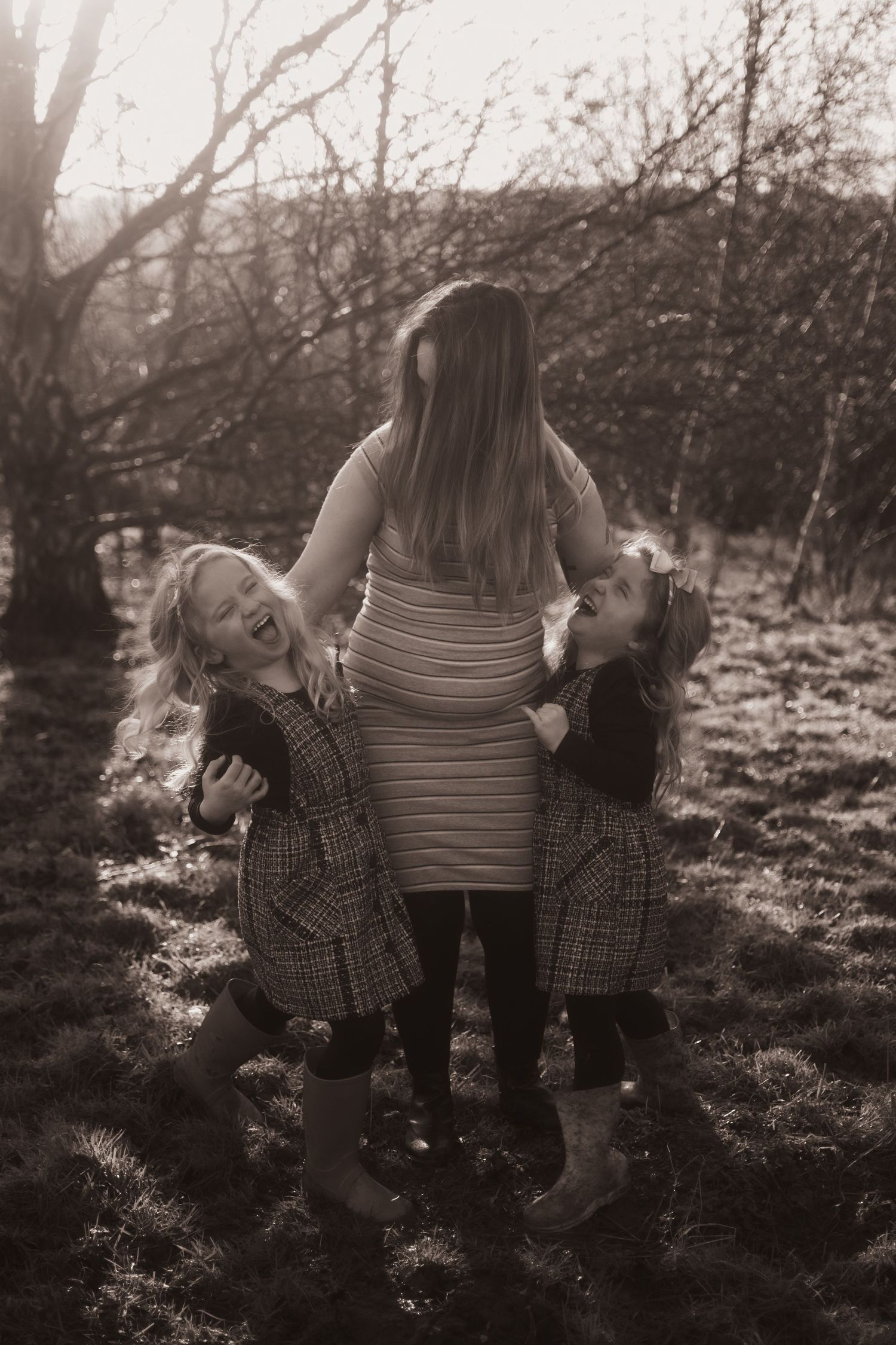 Twin girls cuddling their pregnant mummy