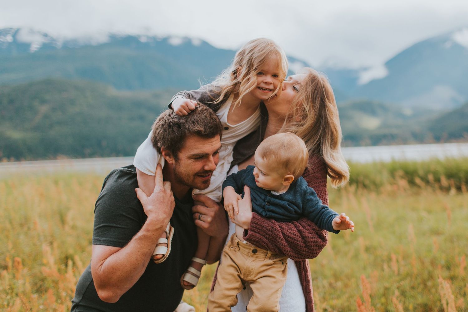 A family  cuddles close together in a mountain meadow in Revelstoke BC