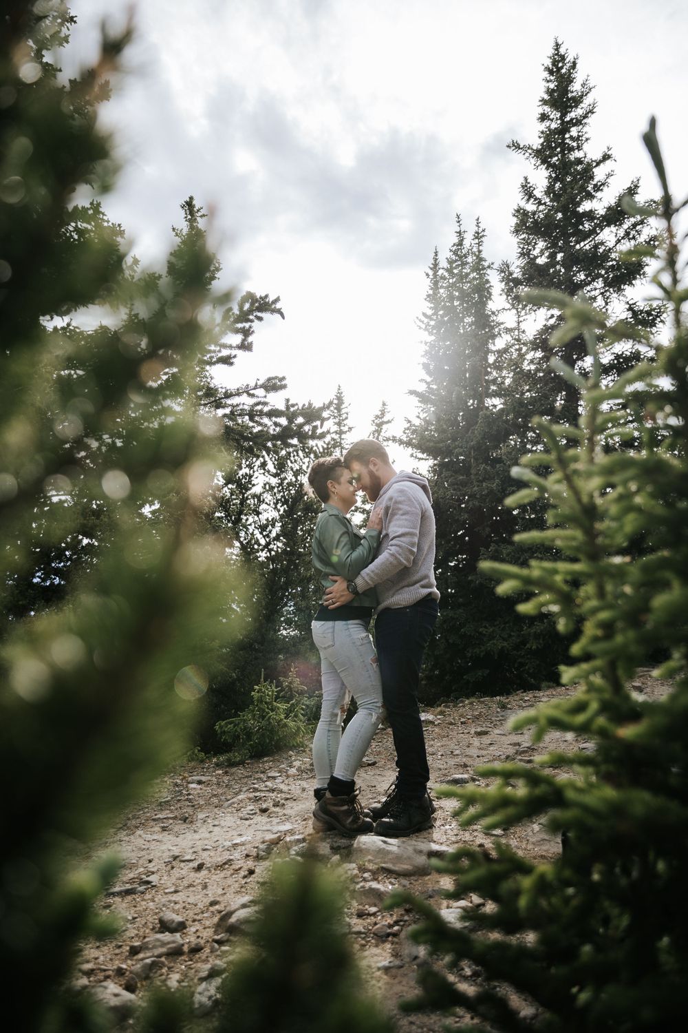 pine trees mountains hiking couple holding each other kissing