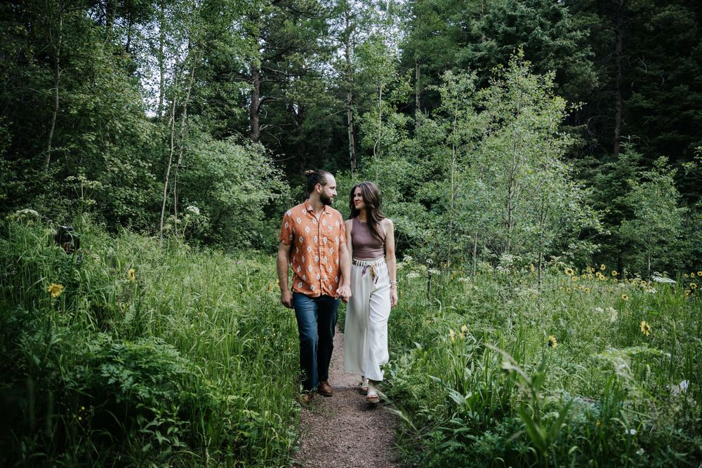 mountains hiking guy in orange shirt man bun girl in cream pants brown top