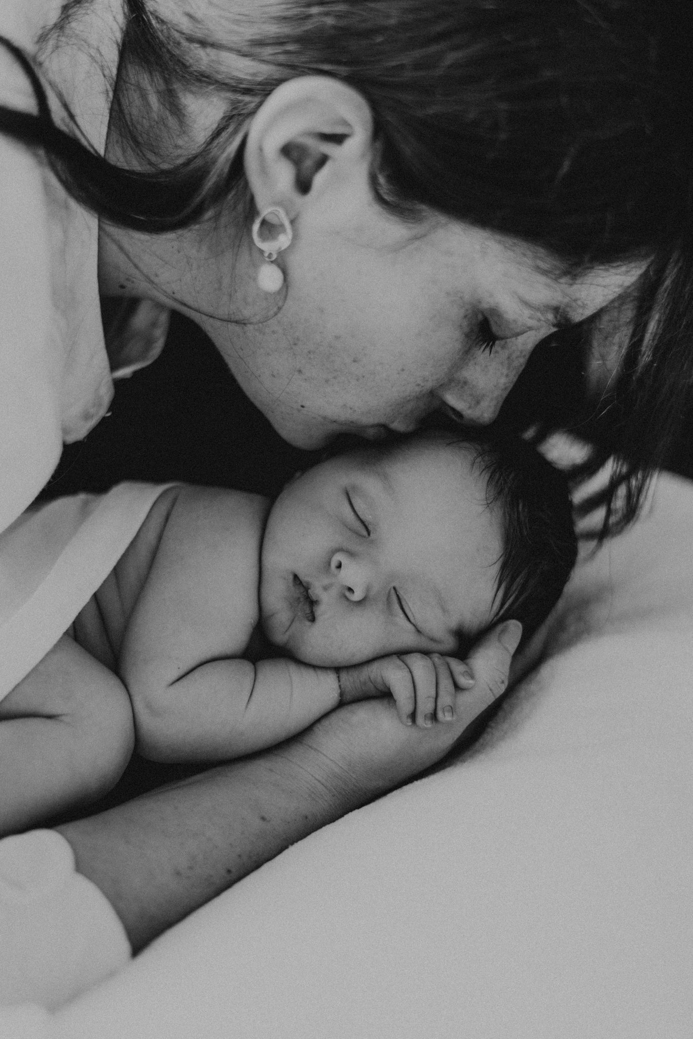 Black and white intimate portrait of parent and sleeping newborn.