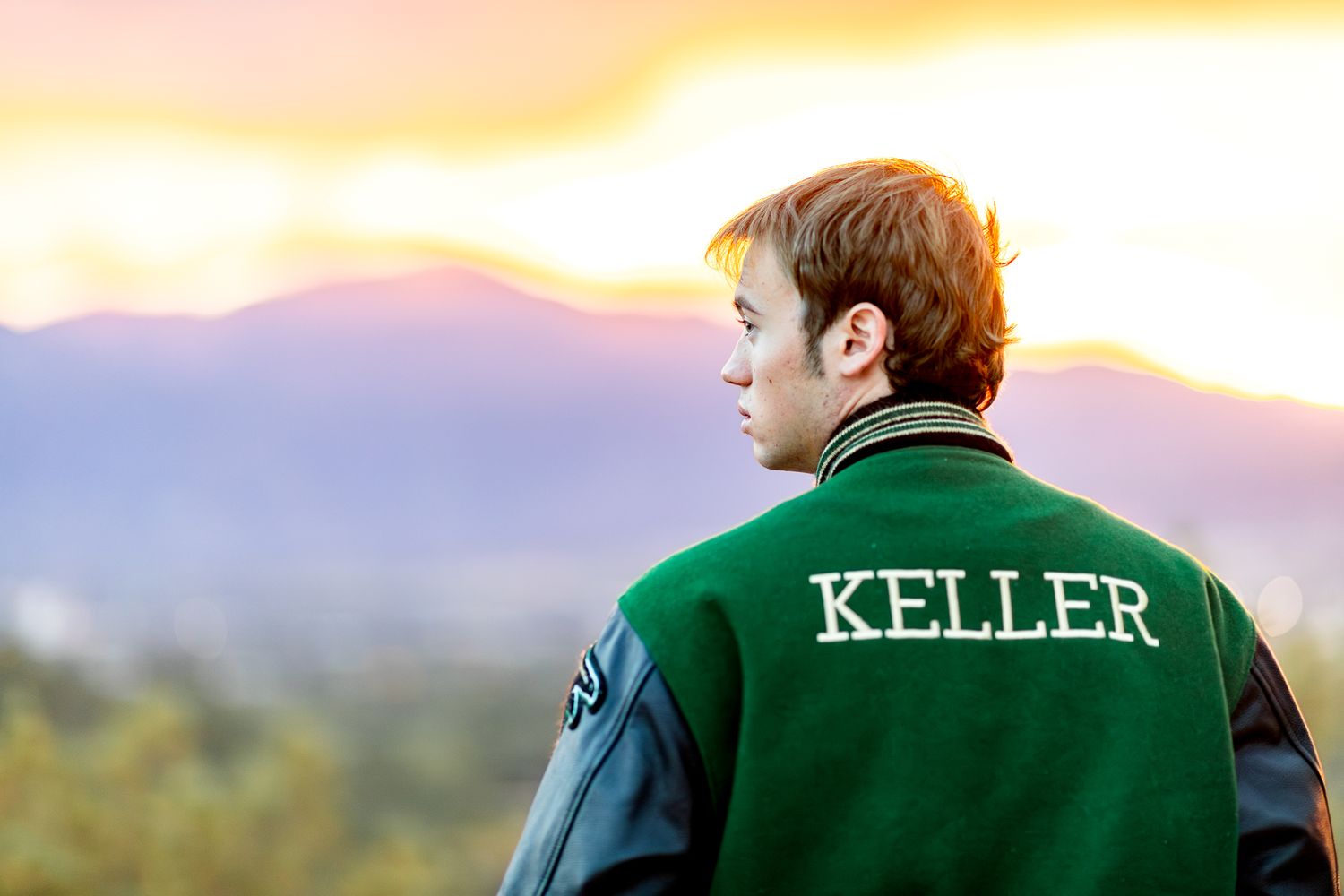 Senior guy faces the colorful sunset over Pikes Peak at his senior session at Palmer Park in Colorado Springs.