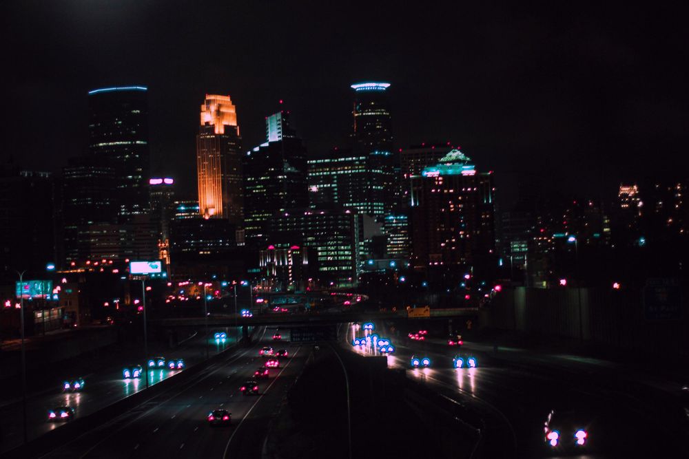 Minneapolis skyline at night with colorful lights reflecting on wet streets.