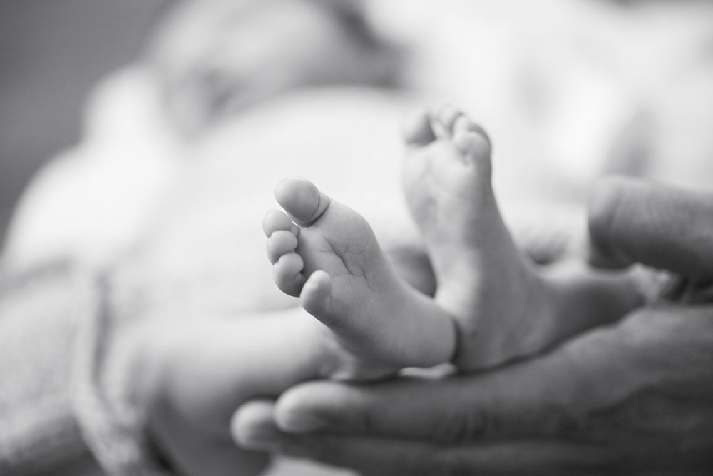 Close-up of newborn baby feet in soft black and white.