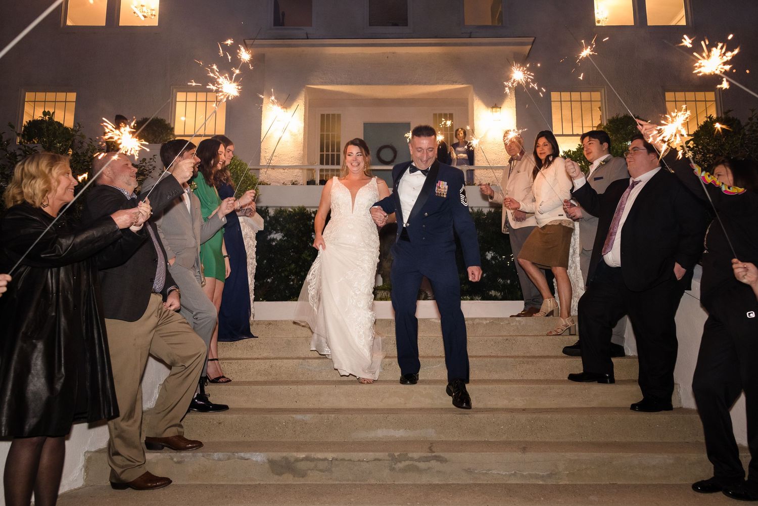 Wedding guests holding sparklers creating a magical nighttime exit pathway.
