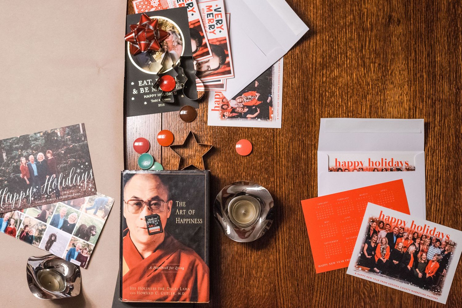 Holiday cards and promotional materials arranged on wooden surface with books and decorative items.