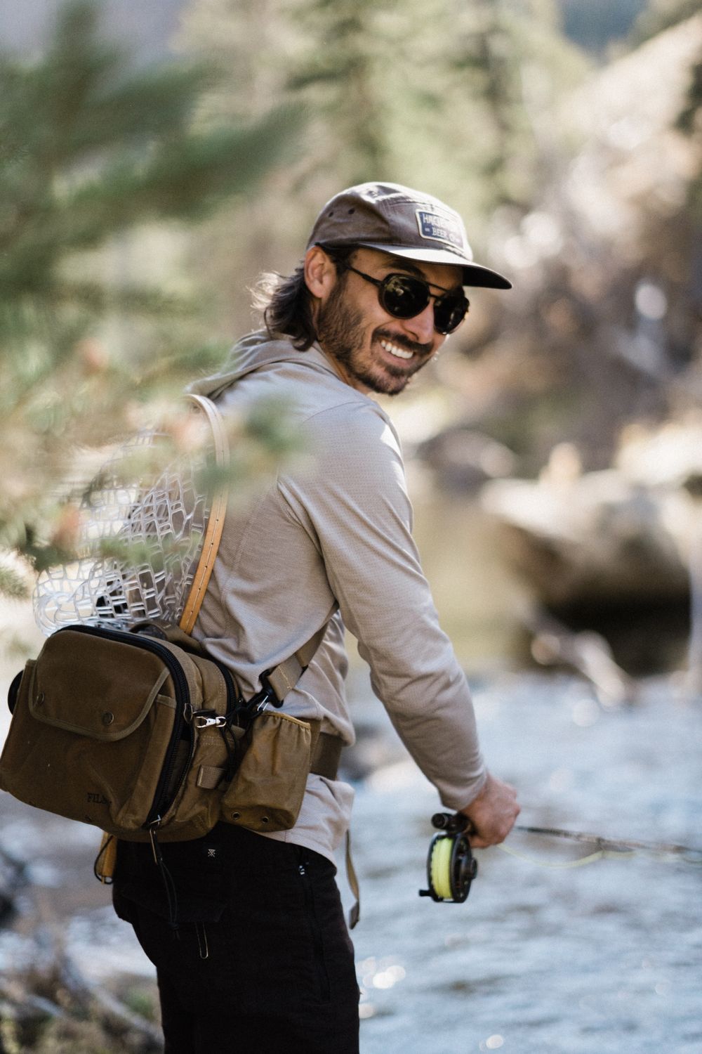 An outdoor enthusiast fishing in a scenic mountain stream with gear and equipment.