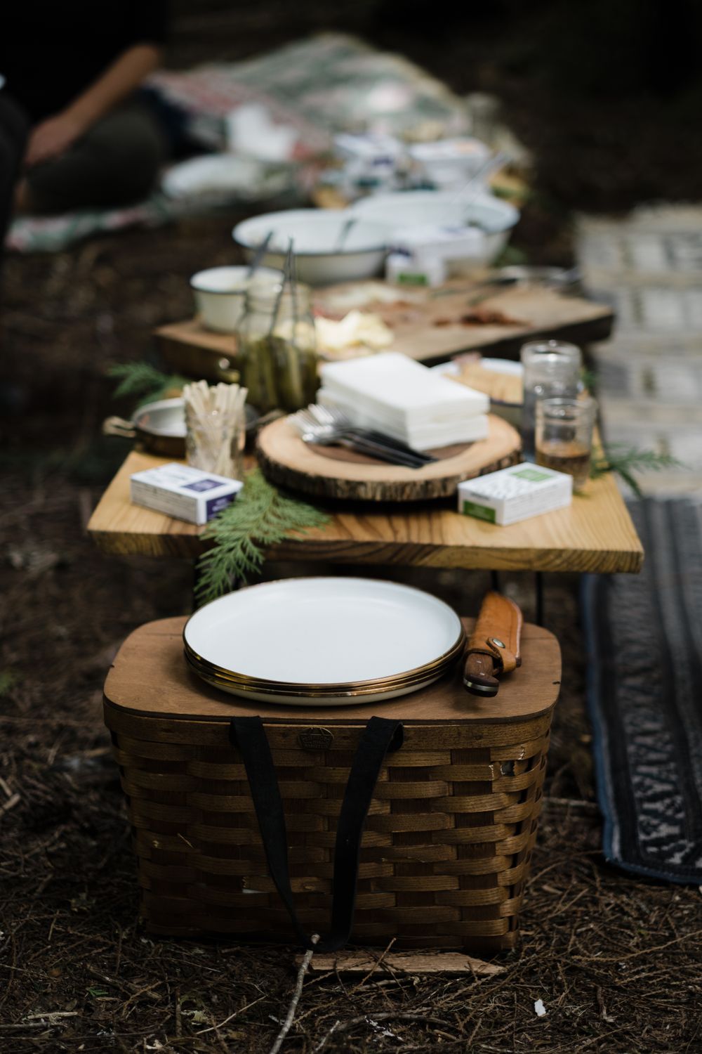 Rustic outdoor table setting with wooden chargers and white plates in nature.