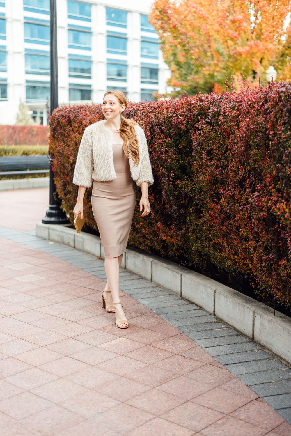 Professional look featuring cream sweater and pencil skirt against autumn foliage.