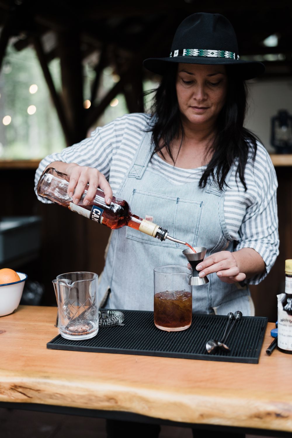 Bartender pouring craft cocktails on a wooden bar with precise measurements.
