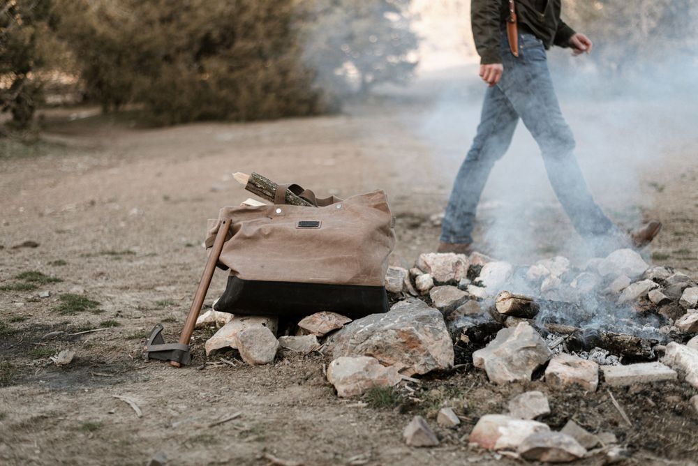 A campfire setup with rocks arranged in a circle and smoke rising from the flames.