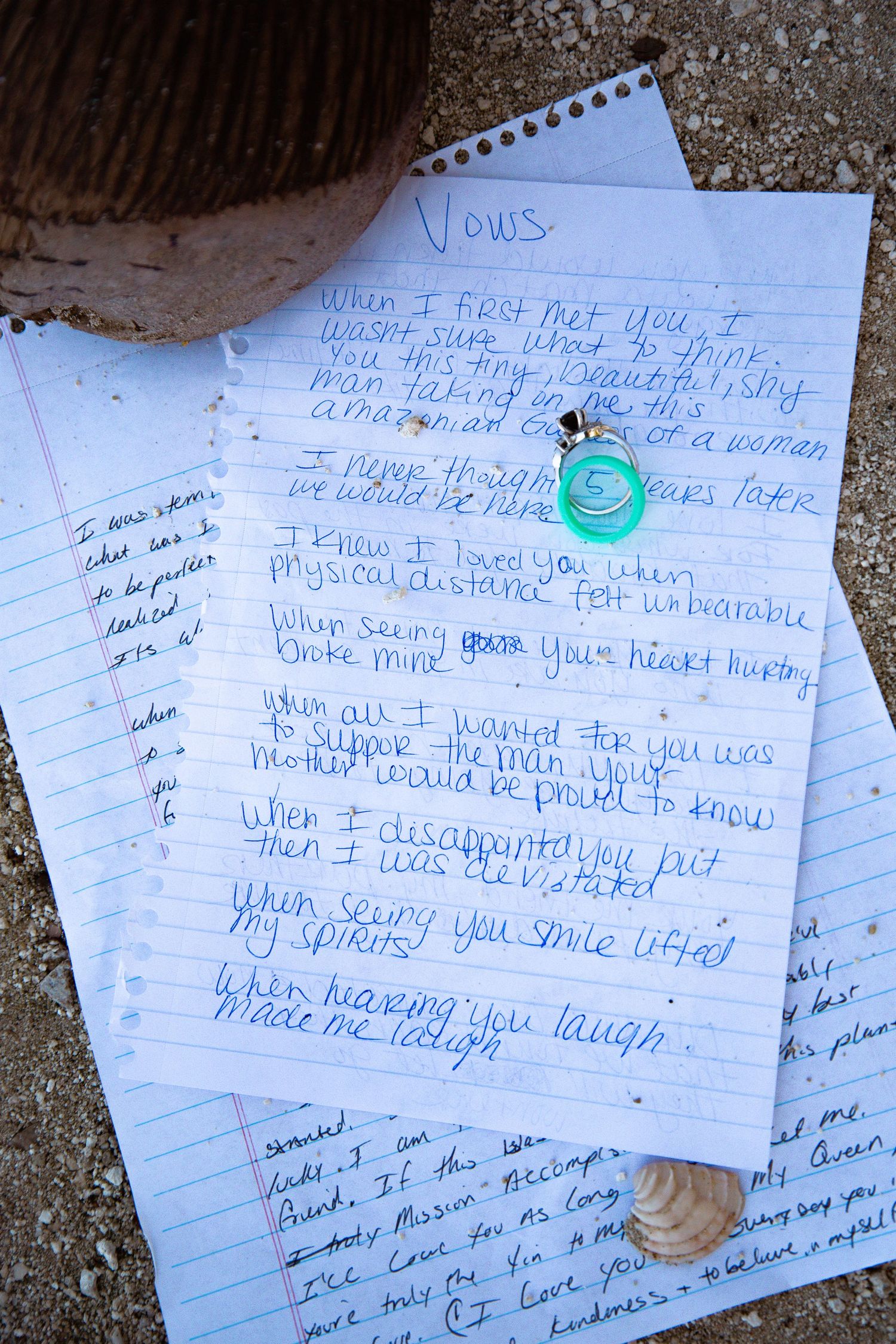 Handwritten wedding vows on notebook paper with seashells and teal decorative elements.