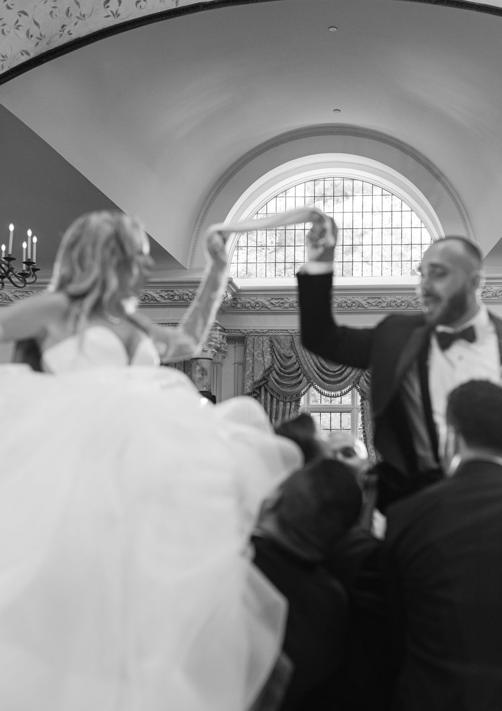 Wedding celebration captured in motion as couple dances under an ornate arched ceiling.