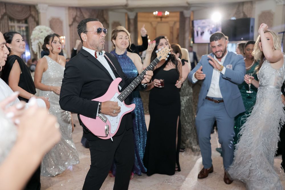 Wedding party dancing and celebrating with a pink guitar on the dance floor.