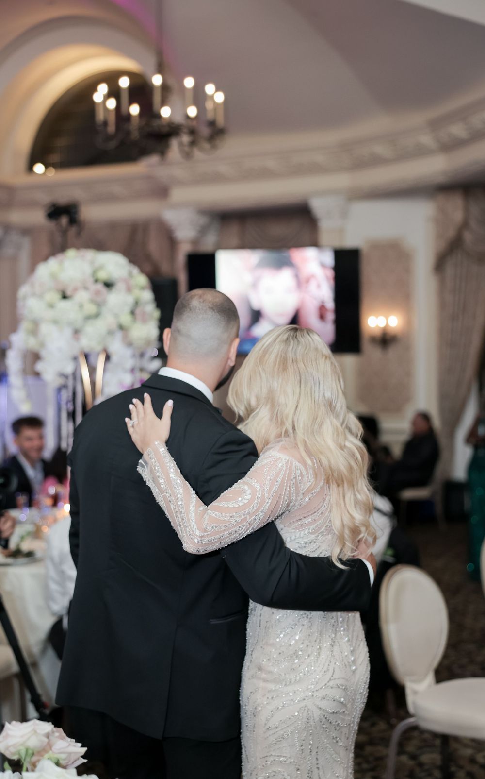Couple sharing an intimate moment during their wedding reception with floral centerpieces.