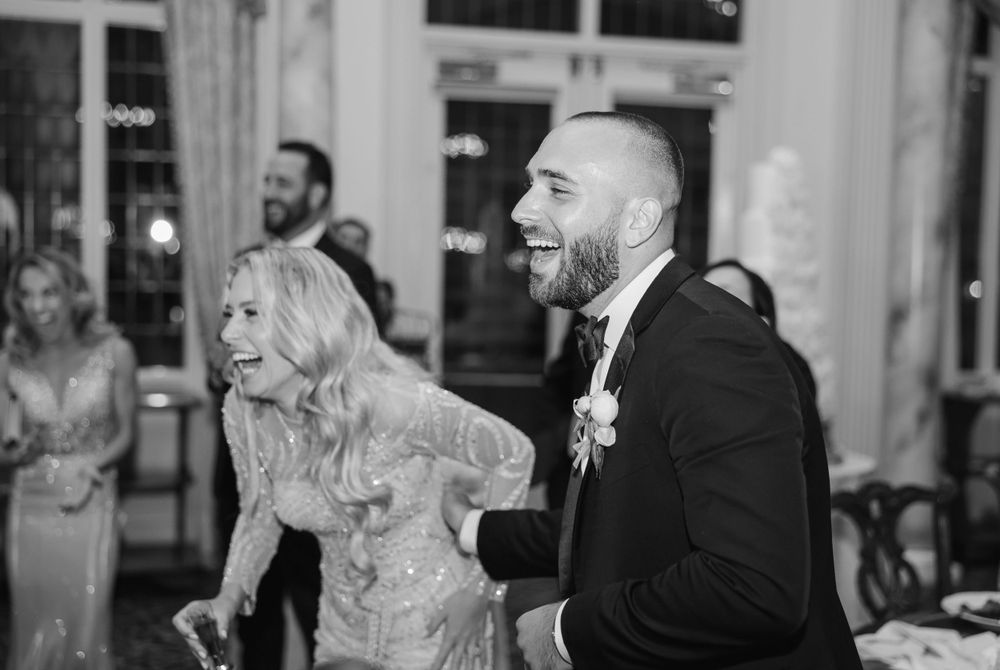 Black and white candid shot of guests enjoying dance moves at a wedding celebration.