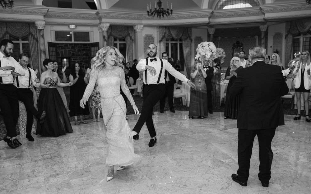 Black and white photo of guests dancing in an elegant ballroom with classic architectural details.