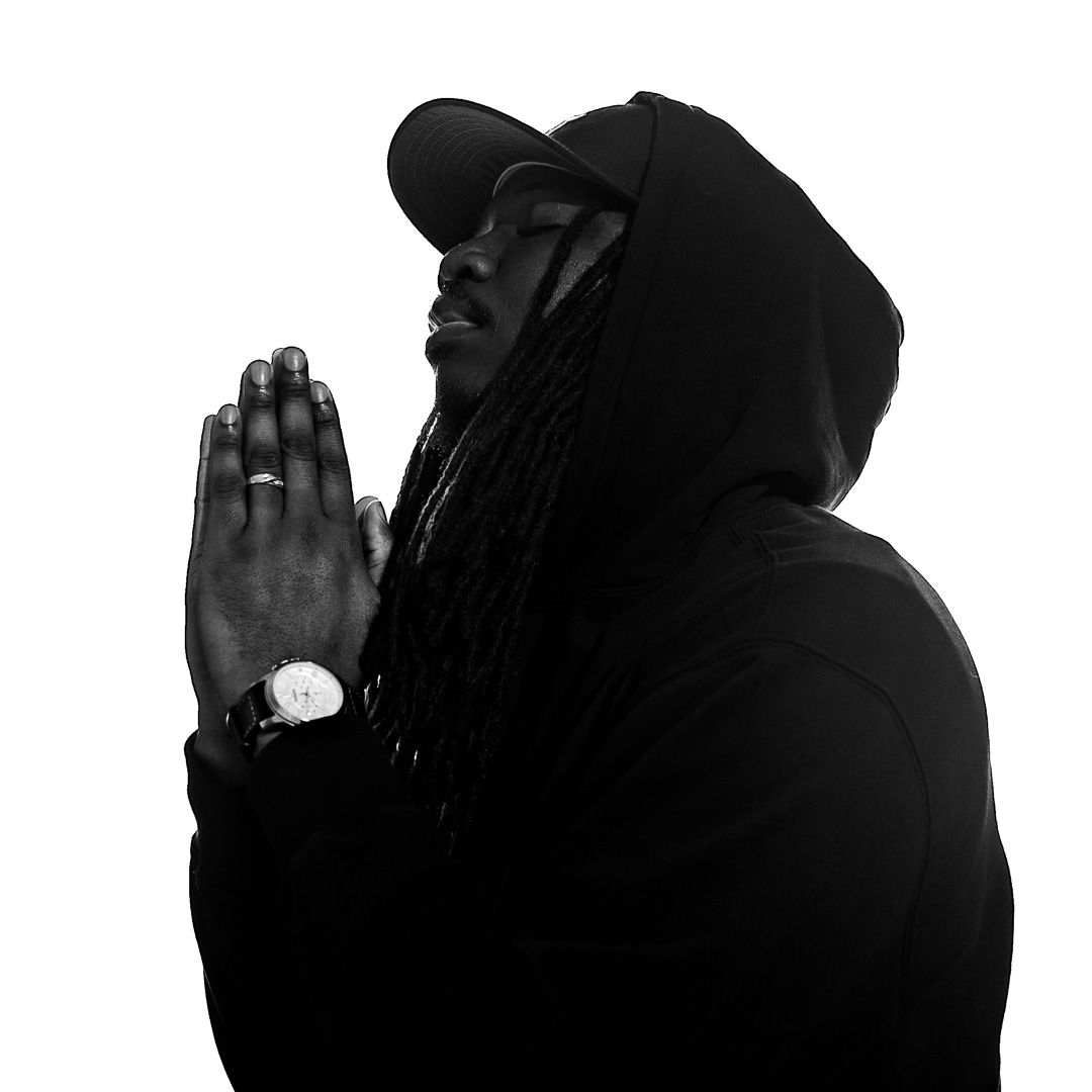 Silhouette profile of person in hoodie with hands clasped in prayer position.