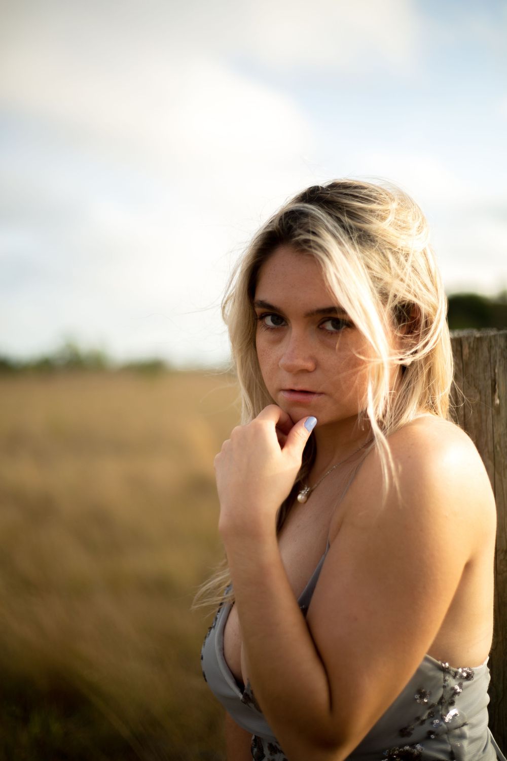 Intimate portrait shot against rustic outdoor backdrop with warm evening lighting.