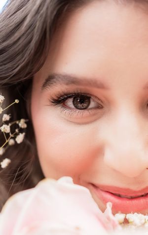 A close-up beauty shot showing eye makeup, soft lighting, and delicate baby's breath flowers.