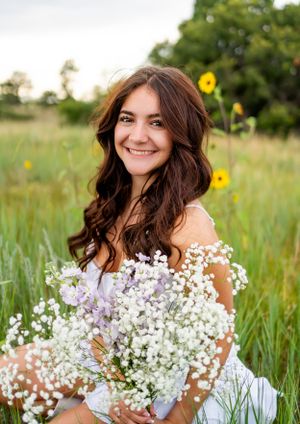 Natural light portrait with baby's breath bouquet surrounded by wildflowers and tall grass.