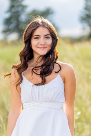 Ethereal summer portrait in white dress against natural meadow backdrop.