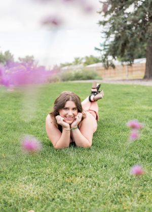 Relaxed outdoor portrait on grass with purple flowers in foreground.