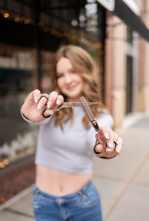 Close-up shot of hands holding professional hairdressing scissors against blurred background.