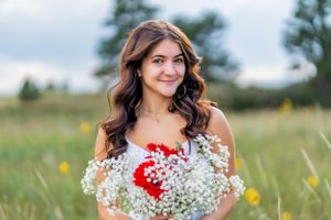 Summer portrait with red and white flower bouquet in a sunlit meadow.