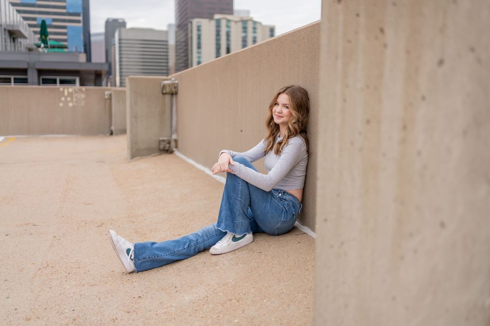 Relaxed lifestyle photo on a rooftop with casual denim and sneakers outfit.