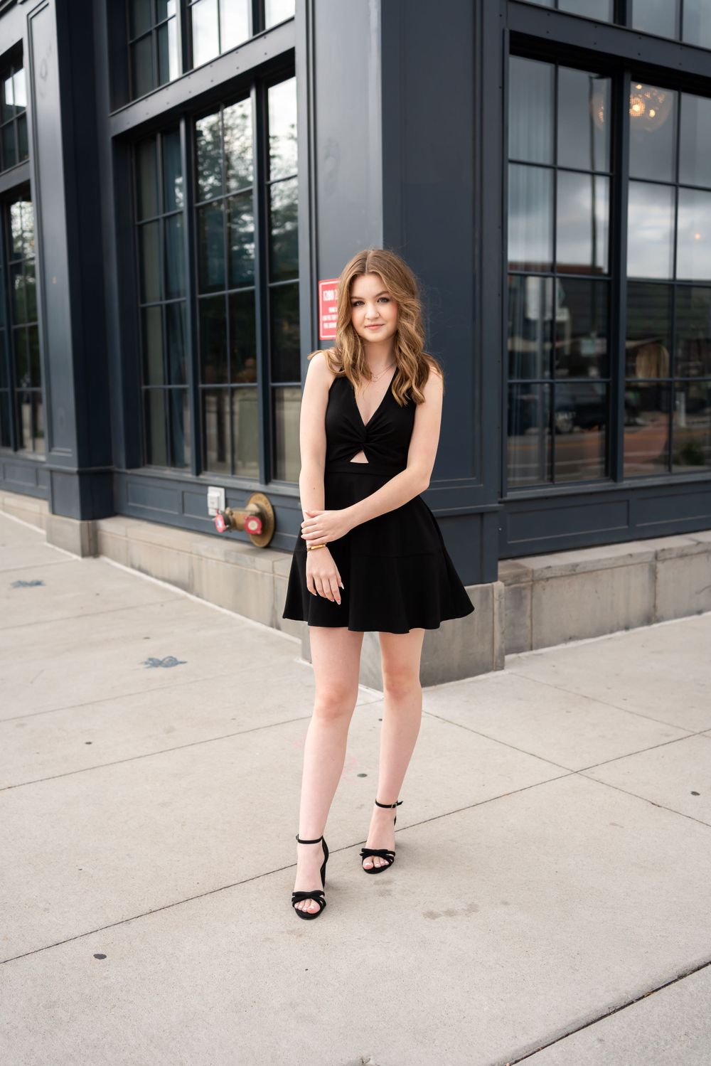Urban fashion photograph on a city sidewalk with architectural elements in background.