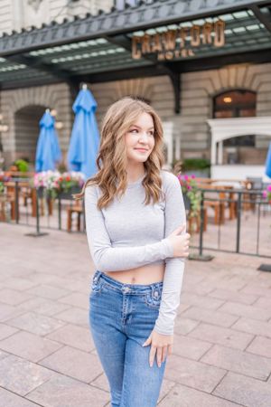 Street style portrait outside restaurant with blue jeans and grey top.