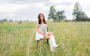 Summer portrait session in a wildflower meadow with white boots and floral accents.