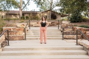 A person in black and pink stands at the center of stone steps with decorative railings.