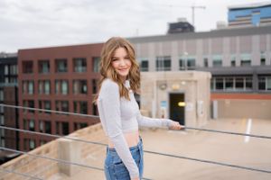 Urban rooftop photo shoot with casual gray top and denim against city buildings.