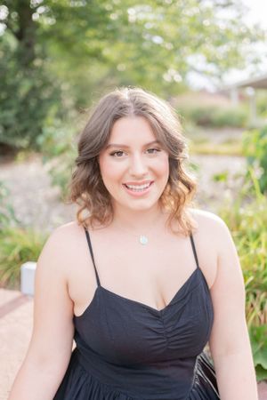 Summer portrait in a black dress surrounded by lush garden greenery.