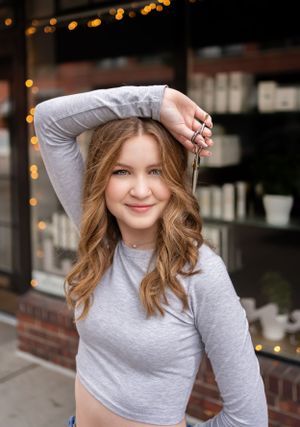 Stylish portrait with gray crop top and wavy hair against string lights.