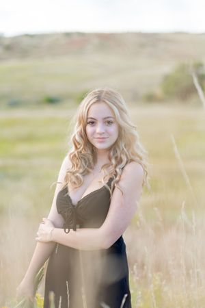 Portrait in meadow with soft golden light and rolling hills in background.