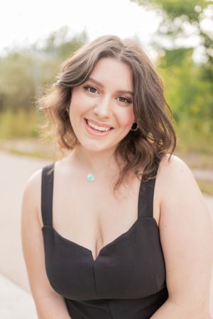 A joyful outdoor portrait featuring a black dress and delicate turquoise necklace.