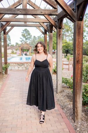 Walking under a rustic wooden pergola in a flowing black dress.