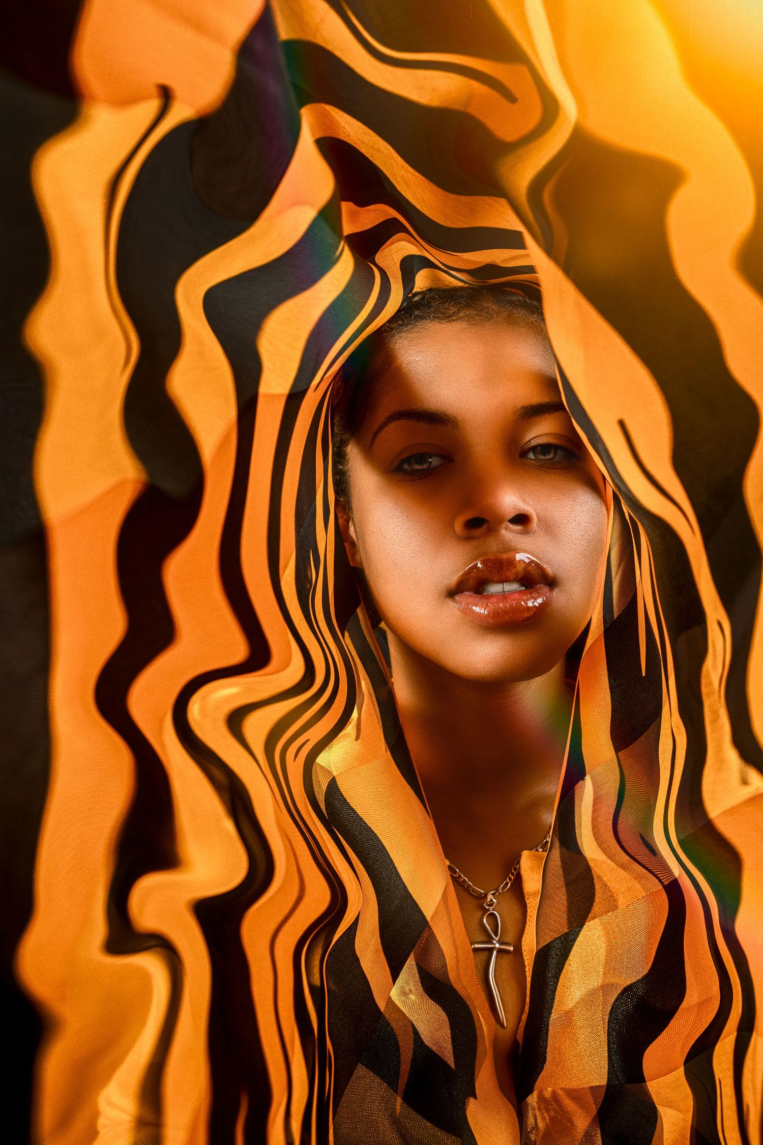 Abstract portrait with wavy orange and black patterns creating a dynamic ripple effect around the subject wearing a cross necklace.