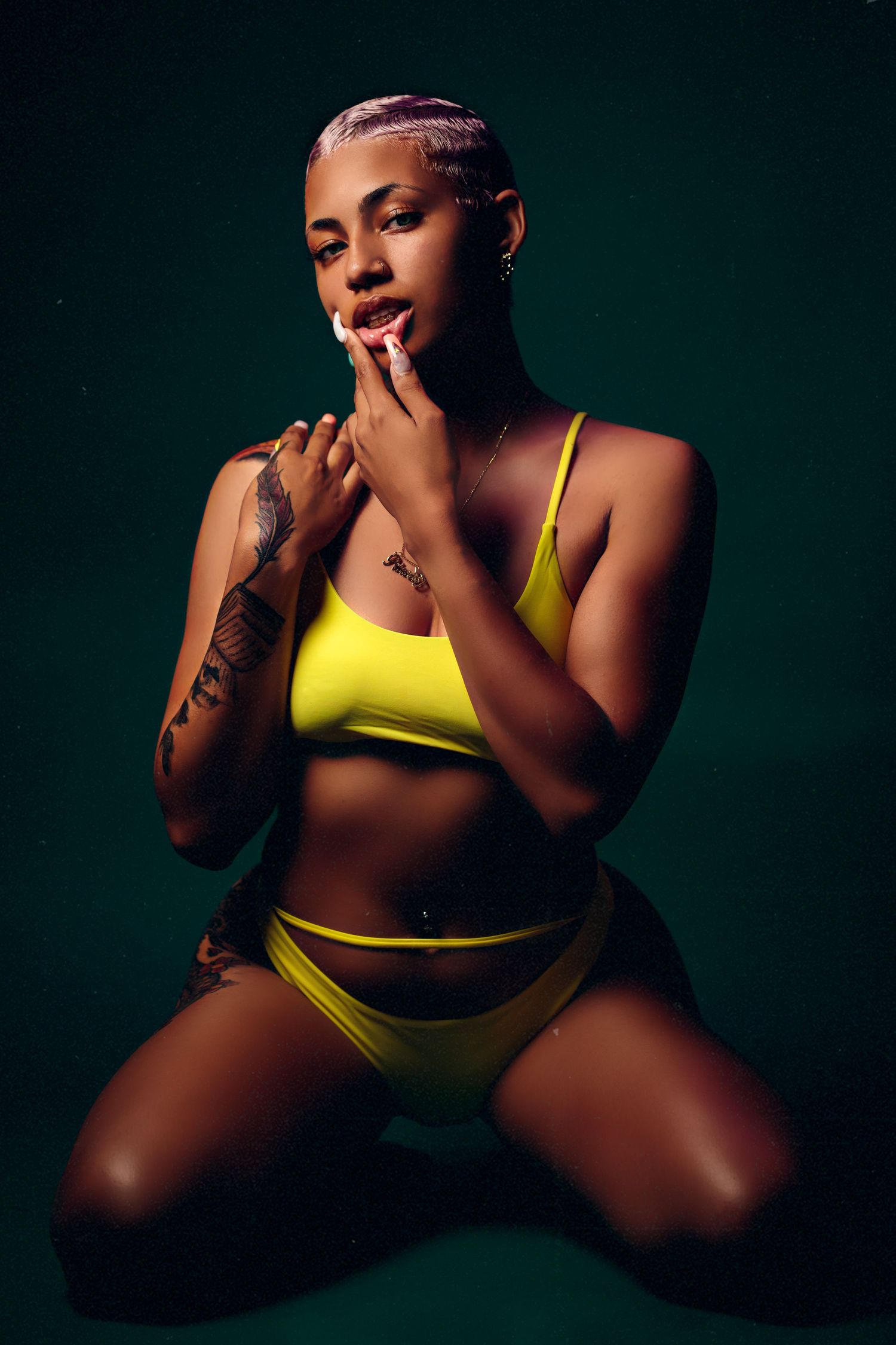 Artistic studio portrait featuring a person in bright yellow athletic wear posing against a dark background.