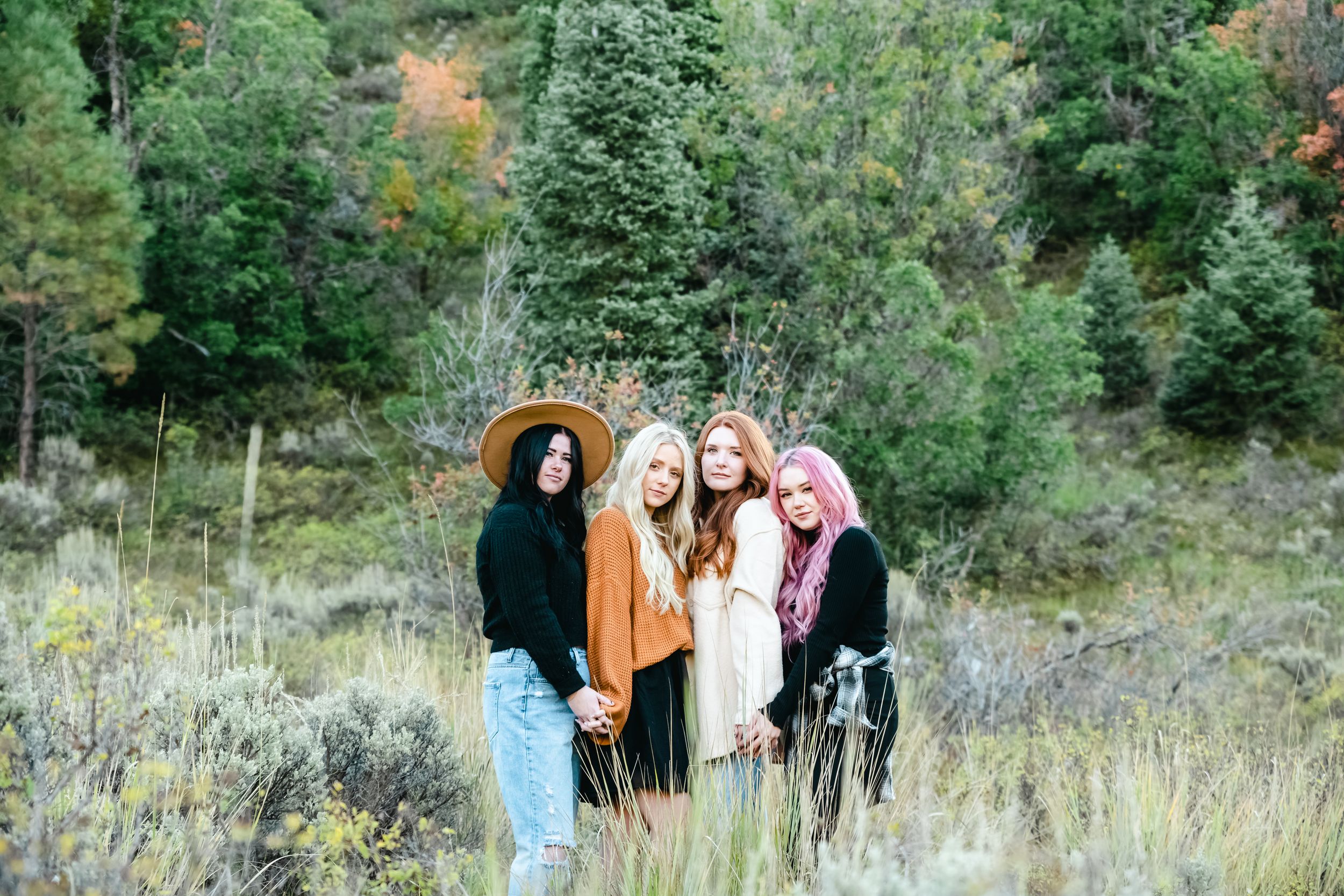 Friends gather for a photo in a scenic autumn mountain setting with colorful trees.